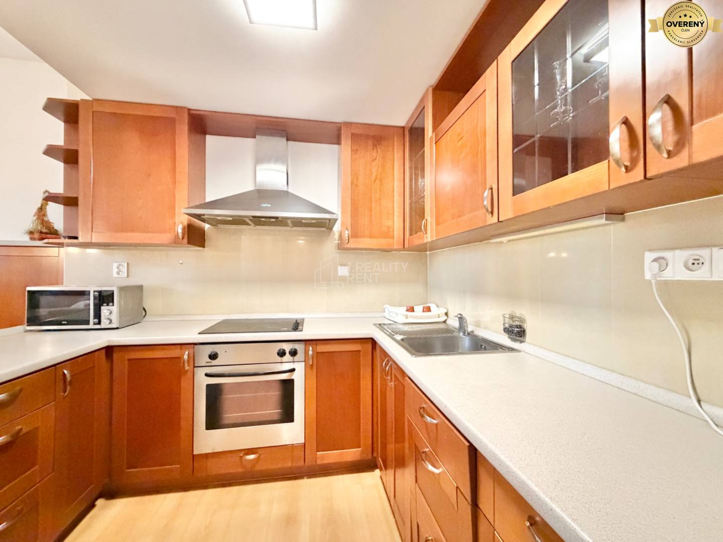 Kuchynská linka s dreveným dekorom v 3-izbovom byte; zahŕňa sporák a mikrovlnku.