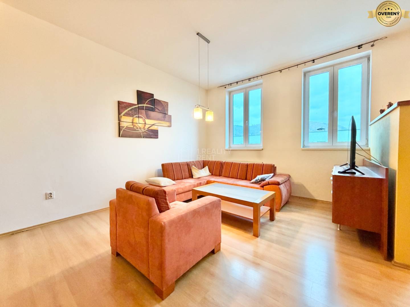 Obývačka v 3-izbovom byte s oranžovou sedačkou a podlahou s dreveným dekorom.