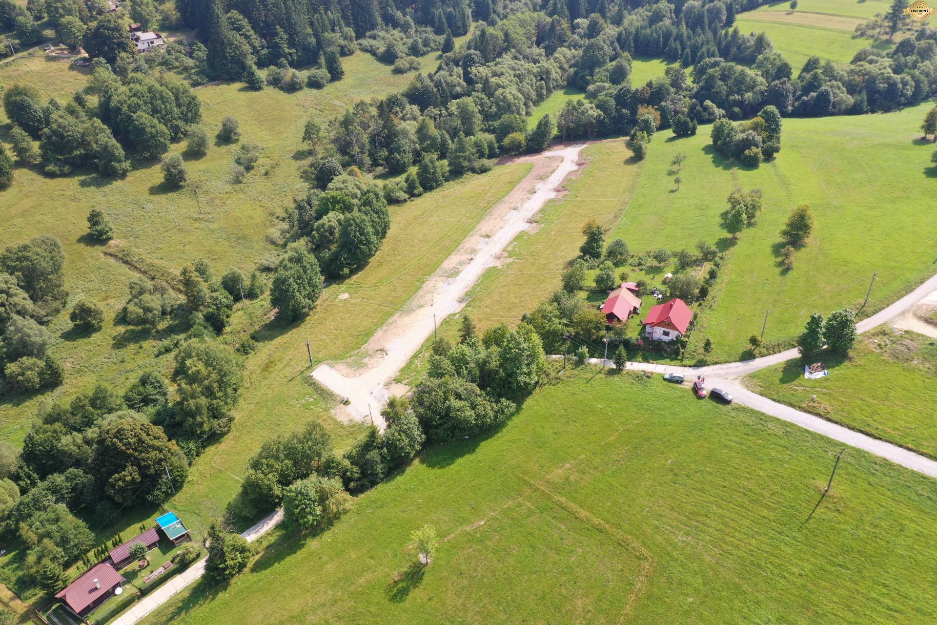 Letecký pohľad na rekreačné pozemky v obci Makov, obklopené zeleňou a domami.