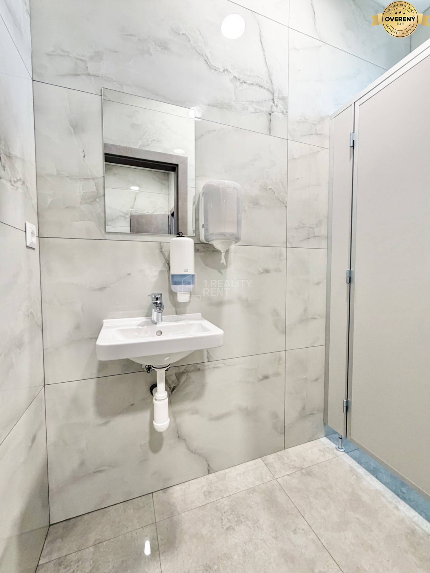 Kúpeľňa s umývadlom v kanceláriách s hladkými stenami a zrkadlom.