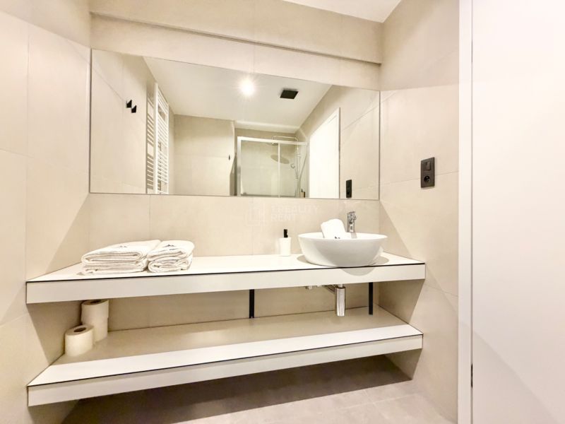 Kúpeľňa s umývadlom a veľkým zrkadlom v Rekreačnom apartmáne.