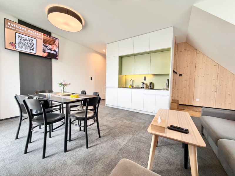 Rekreačný apartmán s kuchynkou, jedálenským stolom a podlahou s dreveným dekorom.