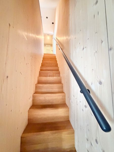 Schodisko v rekreačnom apartmáne s dreveným dekorom a zábradlím v minimalistickom štýle.