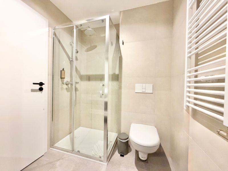 Kúpeľňa v rekreačnom apartmáne s toaletou, sprchovým kútom a svetlými stenami.