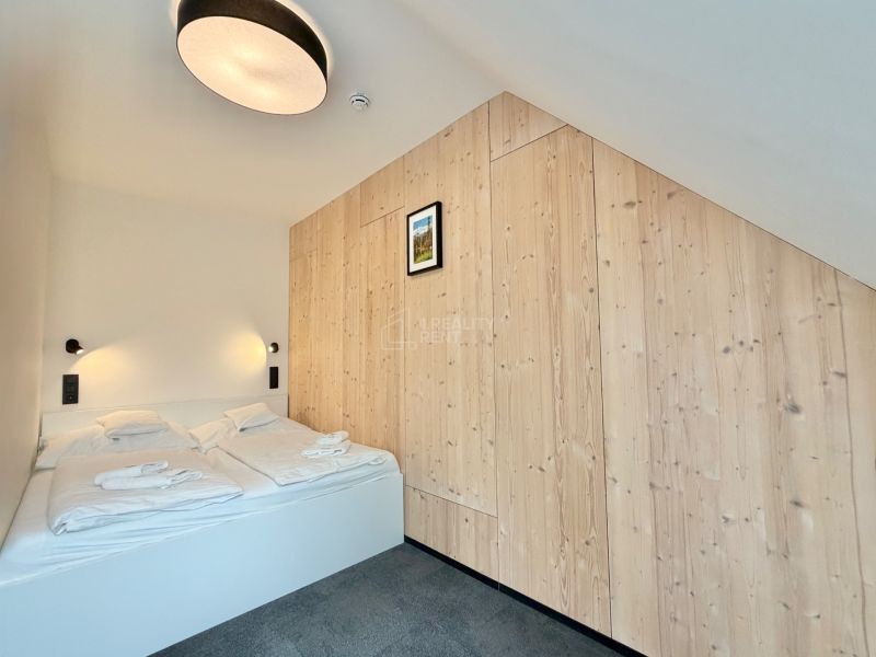 Spálňa v Rekreačnom apartmáne s posteľou a dreveným obkladom steny.
