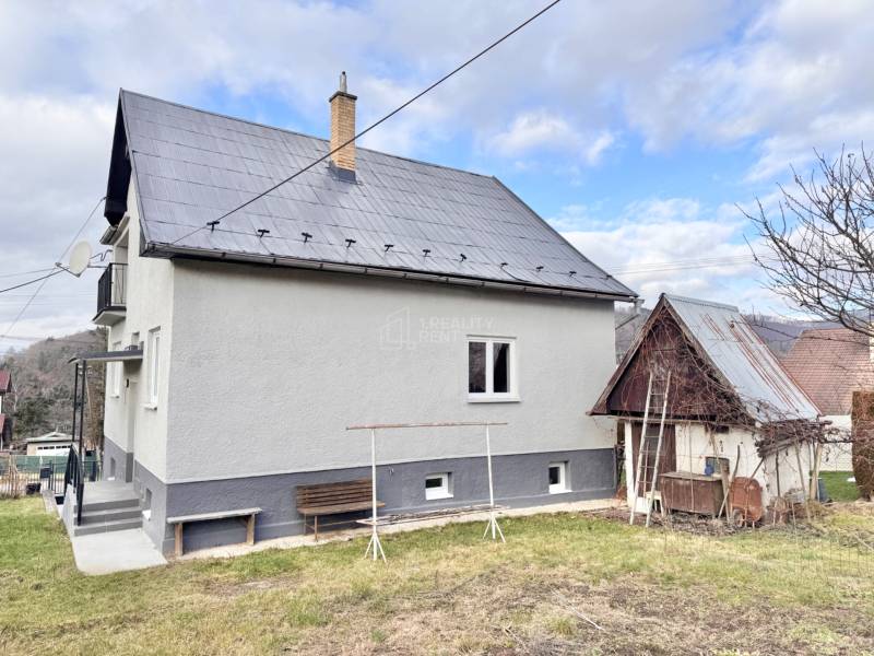 Rodinný dom v Žiline s veľkou záhradou a drevenou prístavbou na pozemku.