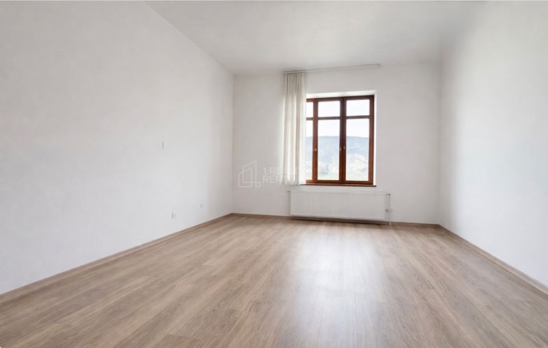 Priestranná miestnosť s podlahou s dreveným dekorom a veľkým oknom v kancelárii.