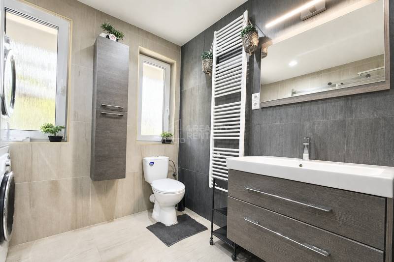 Kúpeľňa s umývadlom, zrkadlom, práčkou a WC.