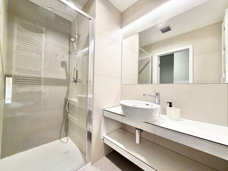 Kúpeľňa v rekreačnom apartmáne s veľkým sprchovým kútom a moderným umývadlom.