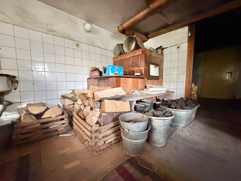 Tradičná kuchyňa v rodinnom dome s pecou, drevom, uhlím a nádobami.