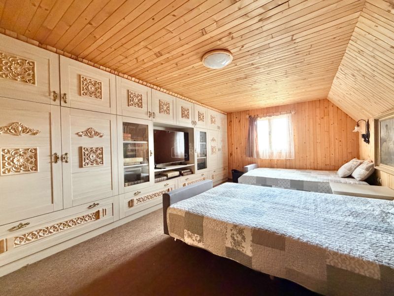 Spálňa v chate so vzorovanou skriňou, dreveným stropom a podlahou s dreveným dekorom.