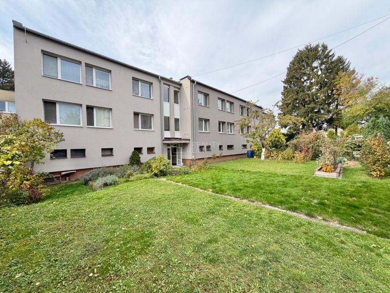 Trojpodlažný bytový dom s trávnikom a stromami na ulici Palackého v Martine.