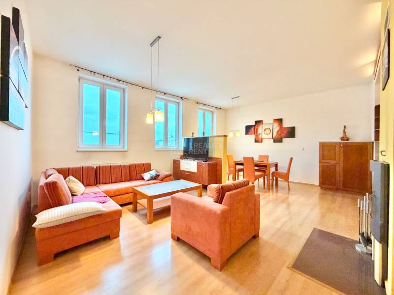 Obývacia izba v 3-izbovom byte s podlahou s dreveným dekorom a pohodlnou sedacou súpravou.